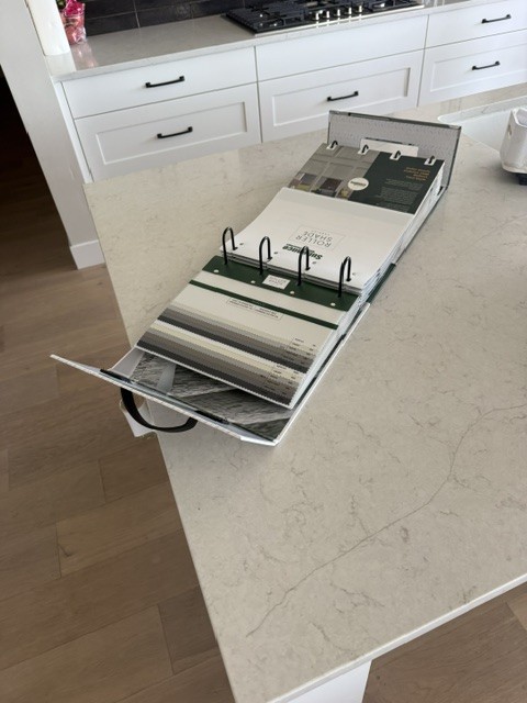 Fabric and color sample consultation book open on a client's kitchen island